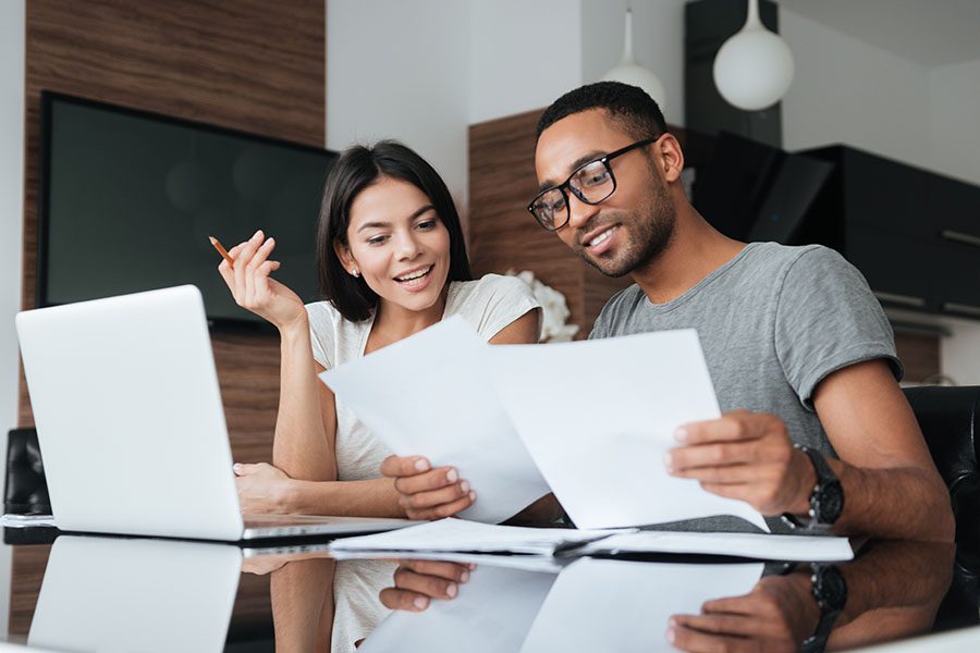 Client Center - Young Couple Reviewing Paperwork and Using Laptop Together